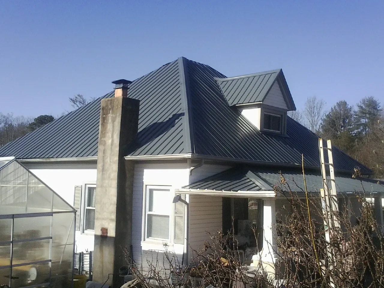 Dark blue standing seam metal roof on a white farmhouse with dormer — Slate & Tile Roof Repair by Roofing Brothers in Towanda
