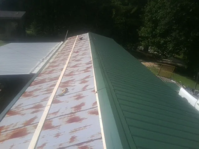 Old rusted panels beside newly installed green metal roofing — Wind Damage Roof Repair by Roofing Brothers in Towanda