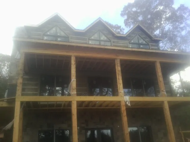 Dormers and porch framing on a large log home under construction — Roof Coating work by our crew in Towanda