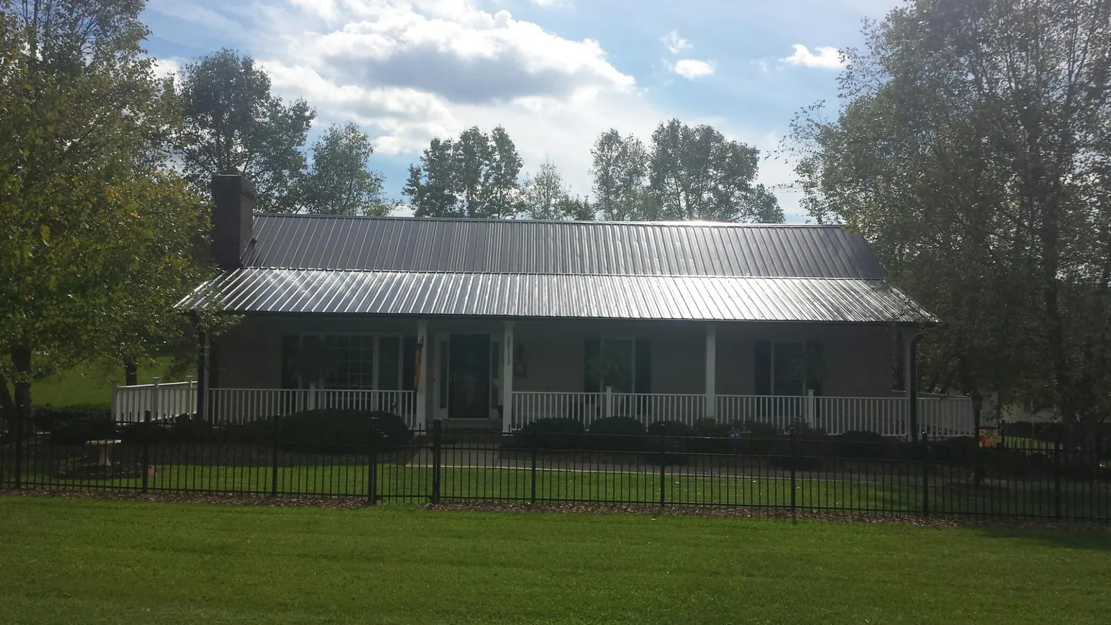 Gray metal roof on a brick ranch with a full width front porch — Gutter Guard Installation work by our crew in Towanda