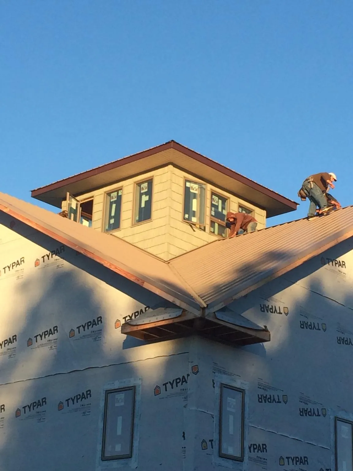 Roofers working around a rooftop cupola on a new metal roof at sunset — Roof Waterproofing in Towanda by Roofing Brothers